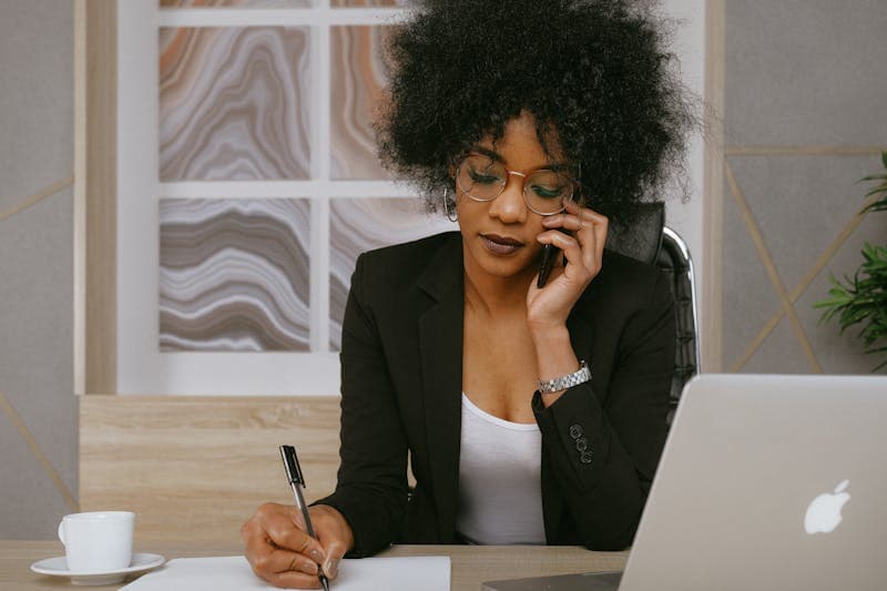 African businesswoman managing orders on phone and laptop